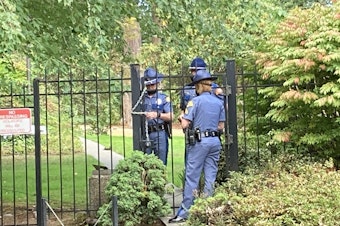 caption:  Washington State Patrol troopers use a chain to secure a gate at the governor's residence following a security breach on Wednesday, September 15, 2021. 