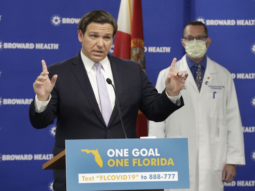 caption: Florida Gov. Ron DeSantis, left, speaks during a news conference along with Dr. Joshua Lenchus, chief medical officer of Broward Health Medical Center on Monday. The number of patients in Florida hospitals for COVID-19 was relatively stable, at just below 8,000 and down from highs above 9,500 nearly two weeks ago.