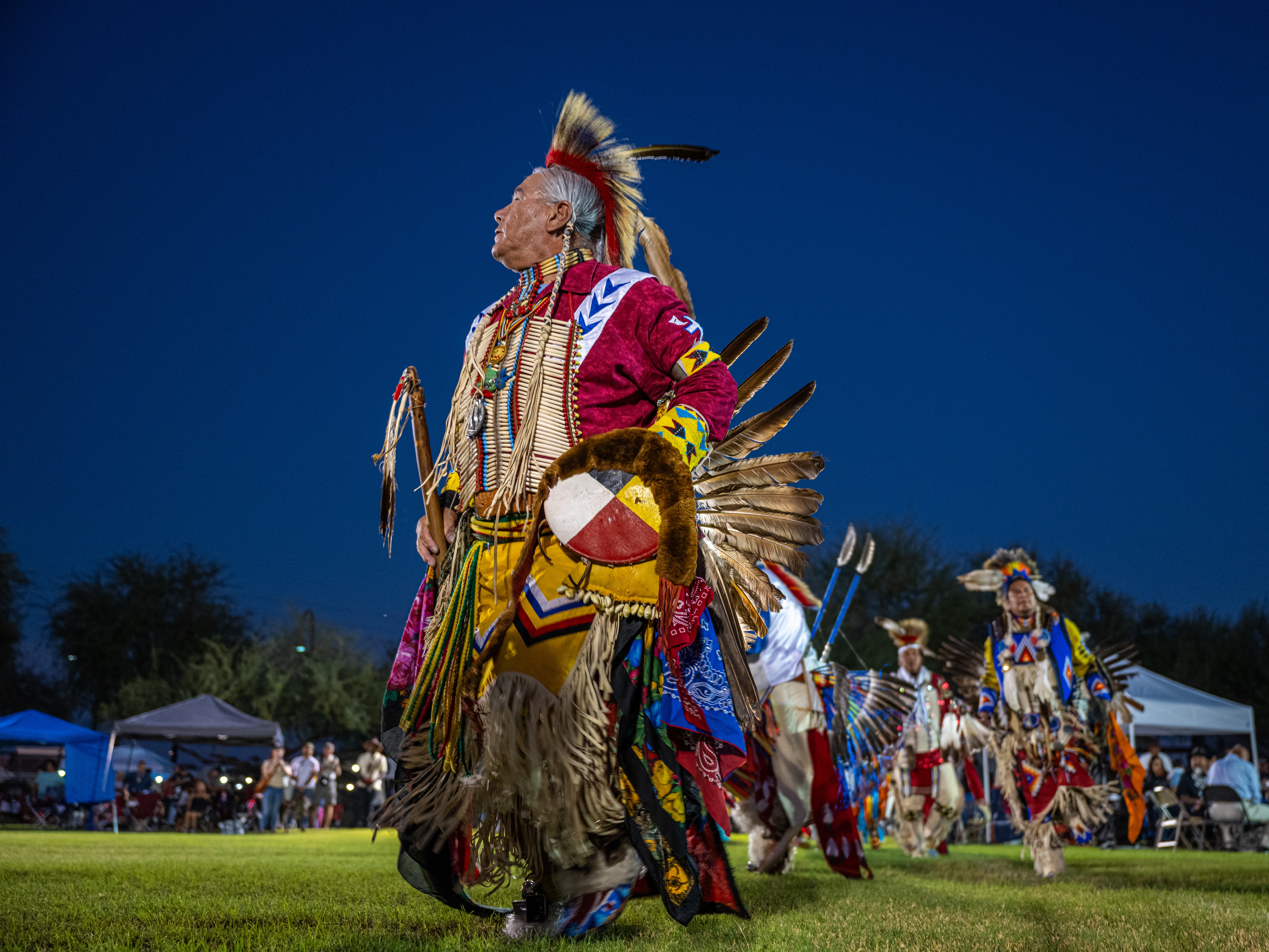caption: Drummers, dancers and other leaders gather to perform and socialize at the Phoenix Indian Center’s Gourd Dance and Social Powwow in the Steele Indian School Park in Phoenix, Ariz., on Oct. 12, 2024.
