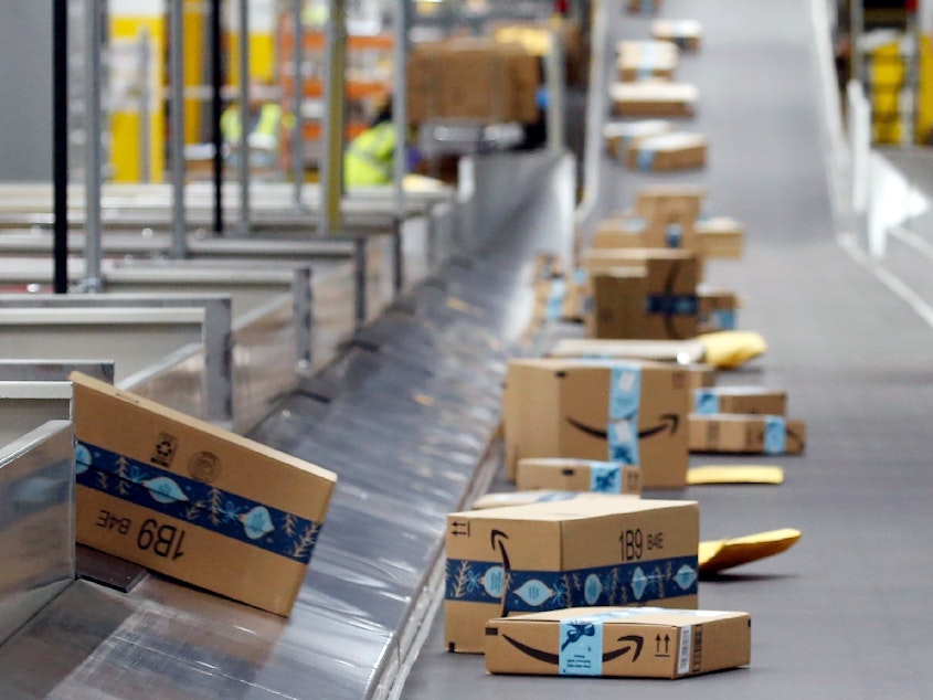 caption: Amazon packages move along a conveyor at an Amazon warehouse in Arizona.