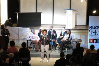 caption: The panel of guest speakers at "Black In Seattle" listen as an audience member adds to the conversation.