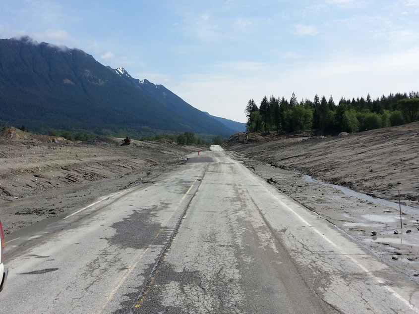 caption: SR 530 is reopening to alternating single-lane traffic May 31. Sections of the roadway was discovered missing during clearing work, so portions of the highway will be unpaved.