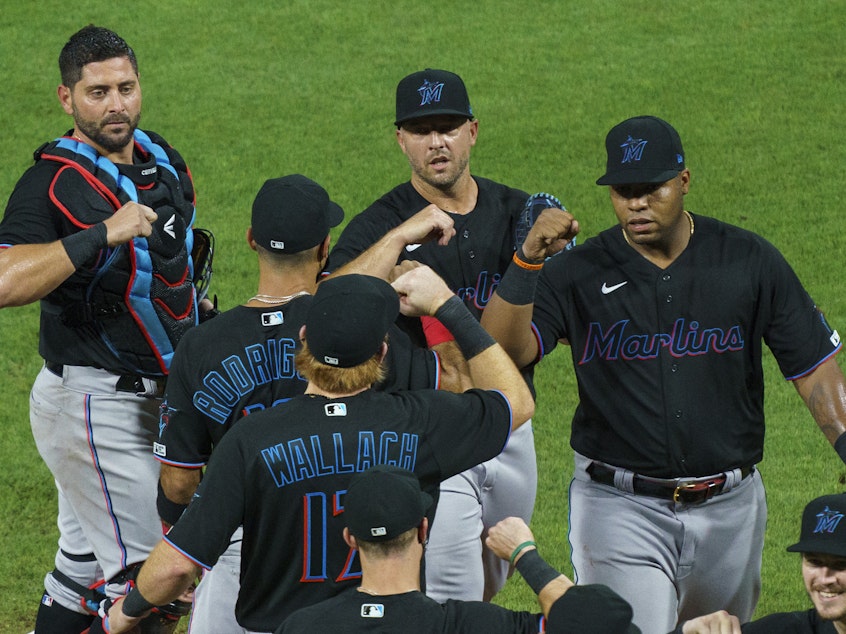 caption: Members of the Miami Marlins celebrate a win with teammates against the Philadelphia Phillies on Friday. The Marlins game on Monday has been postponed.