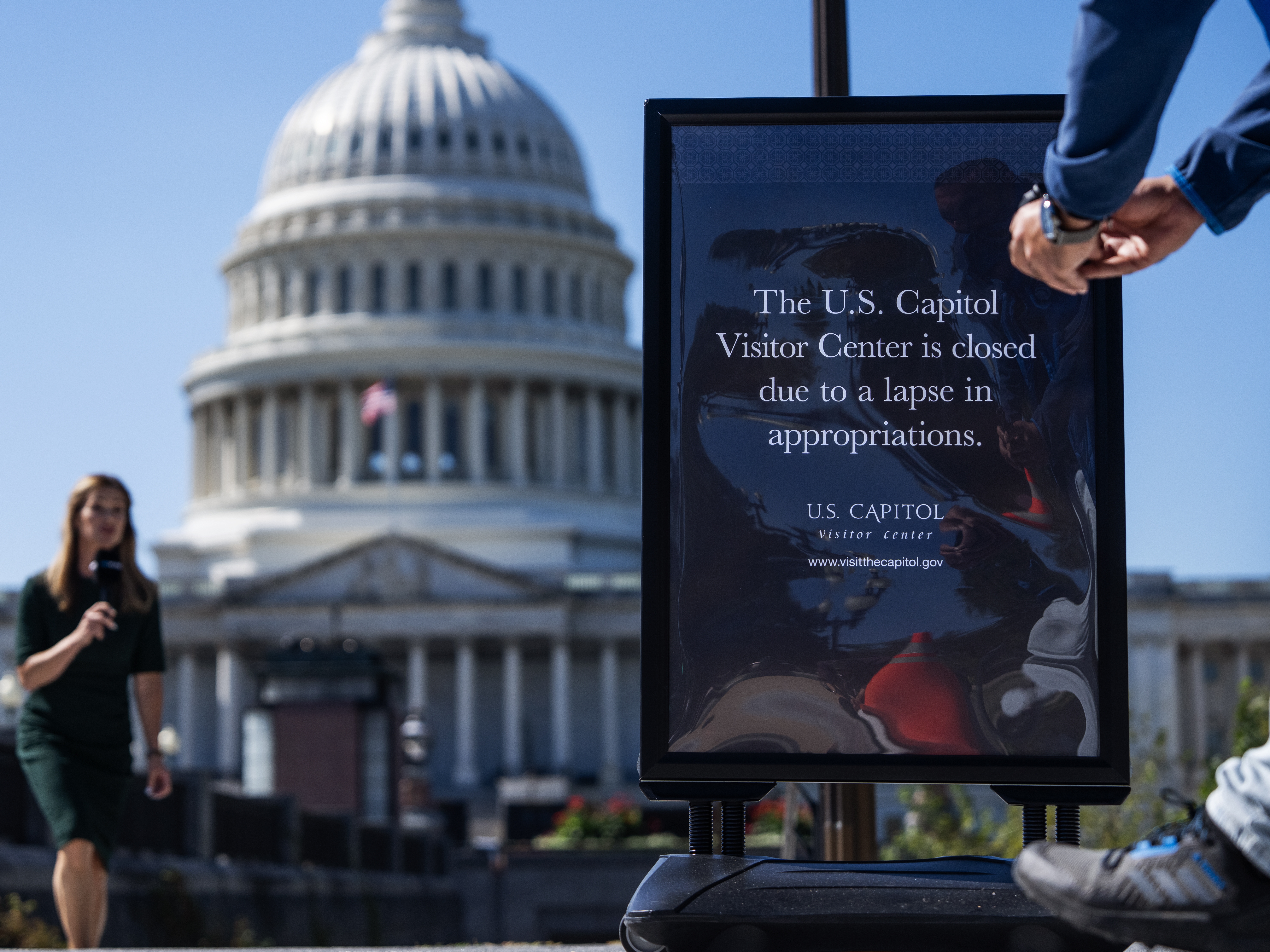caption: A news crew films a segment near a sign indicating that the Capitol Visitor Center is closed due to the government shutdown on Oct. 1.