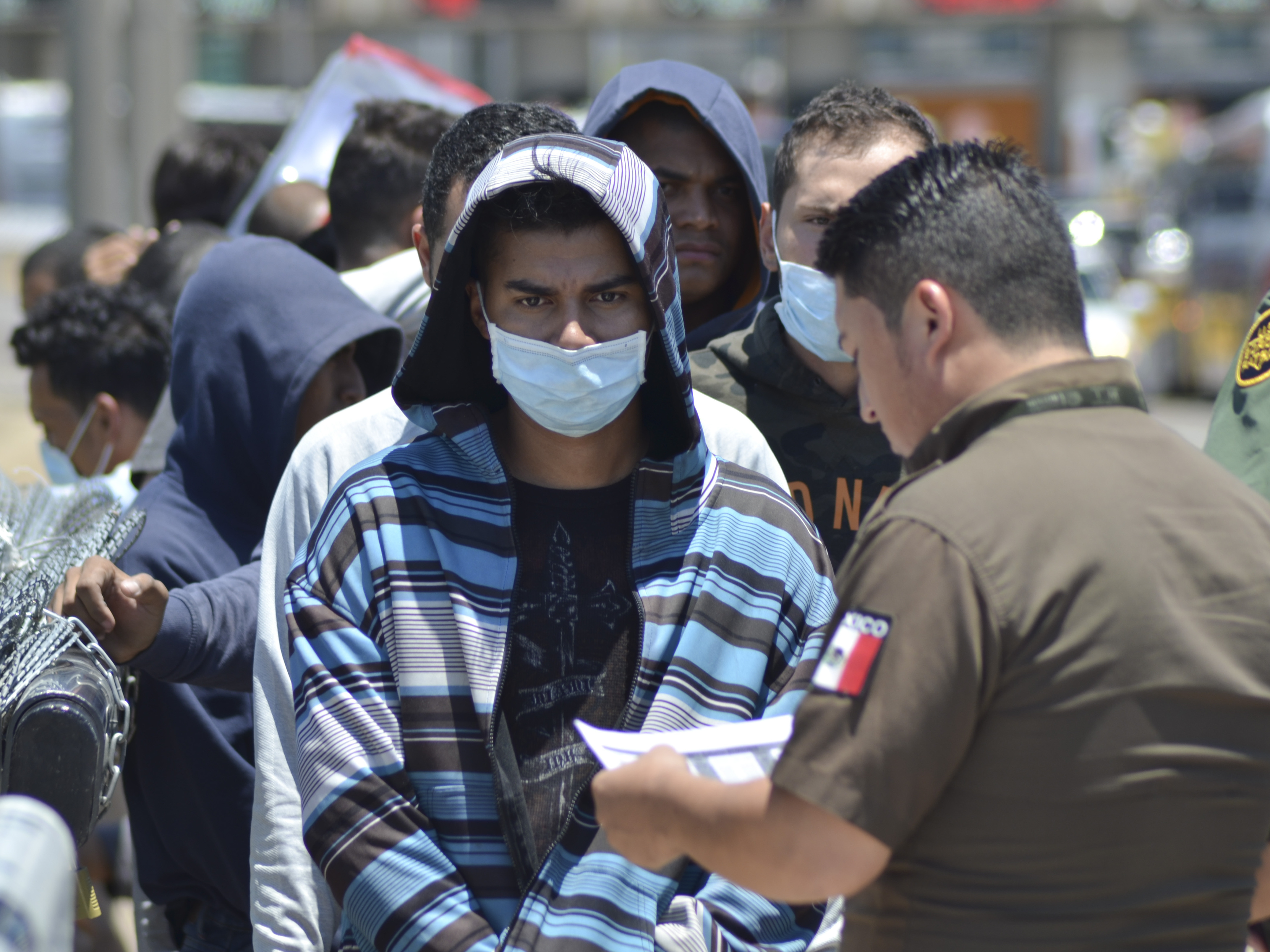 caption: U.S. Border Patrol officers return a group of asylum-seeking migrants to Mexico as Mexican officials check the list, in Nuevo Laredo.