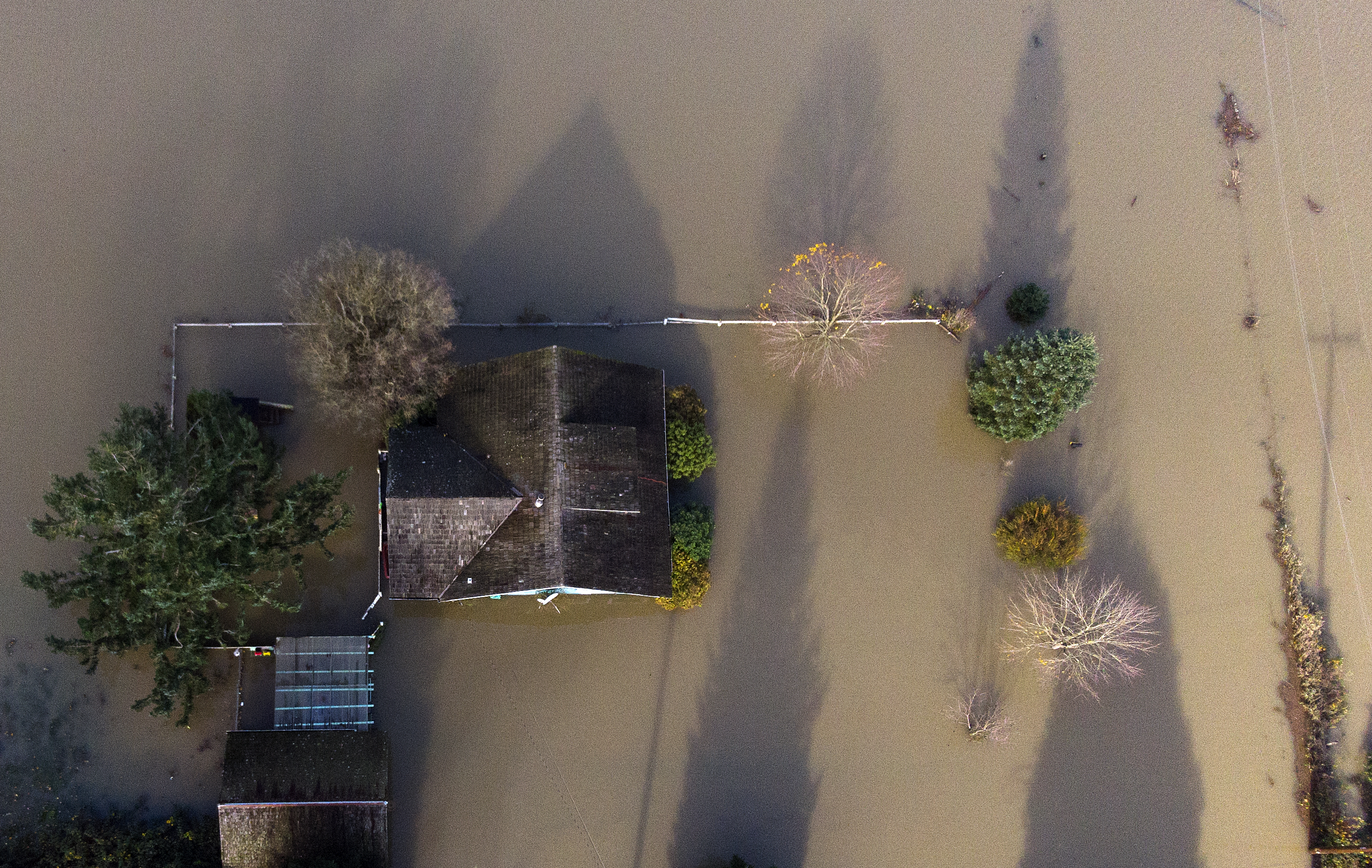 caption: Homes are shown surrounded by flood waters on Tuesday, November 16, 2021, east of Mount Vernon. 