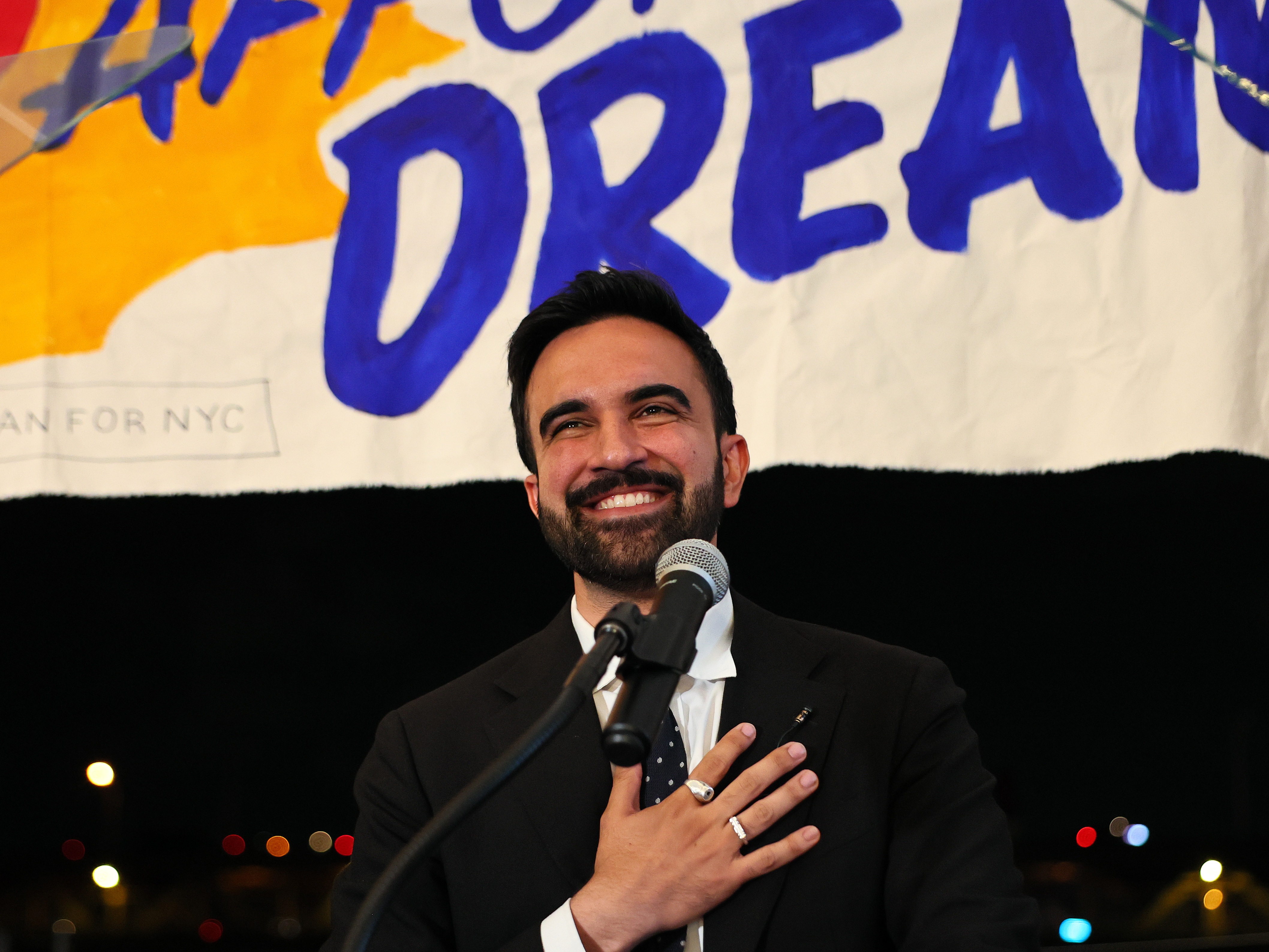 caption: Zohran Mamdani speaks to supporters during a gathering in June.