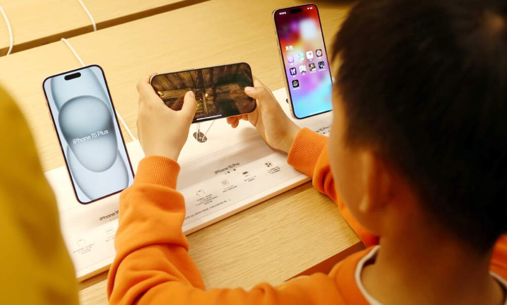 caption: A child tries an e-sports game for the iPhone 15. (CFOTO/Future Publishing via Getty Images)