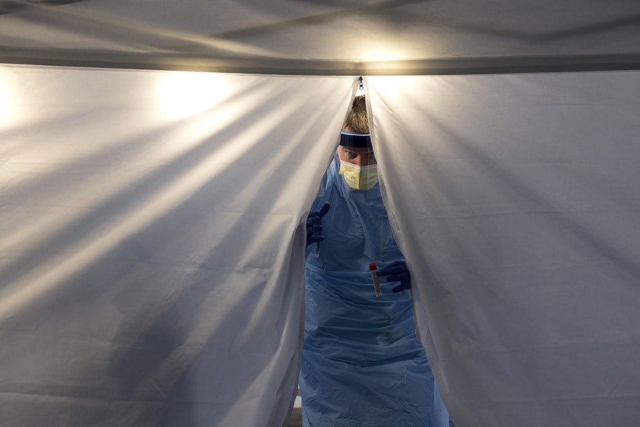 caption: Employee Health Nurse at UW Northwest Hospital Jeff Gates exits a tent at UW Medicine's drive-through coronavirus testing clinic on Thursday, March 12, 2020, in Seattle.