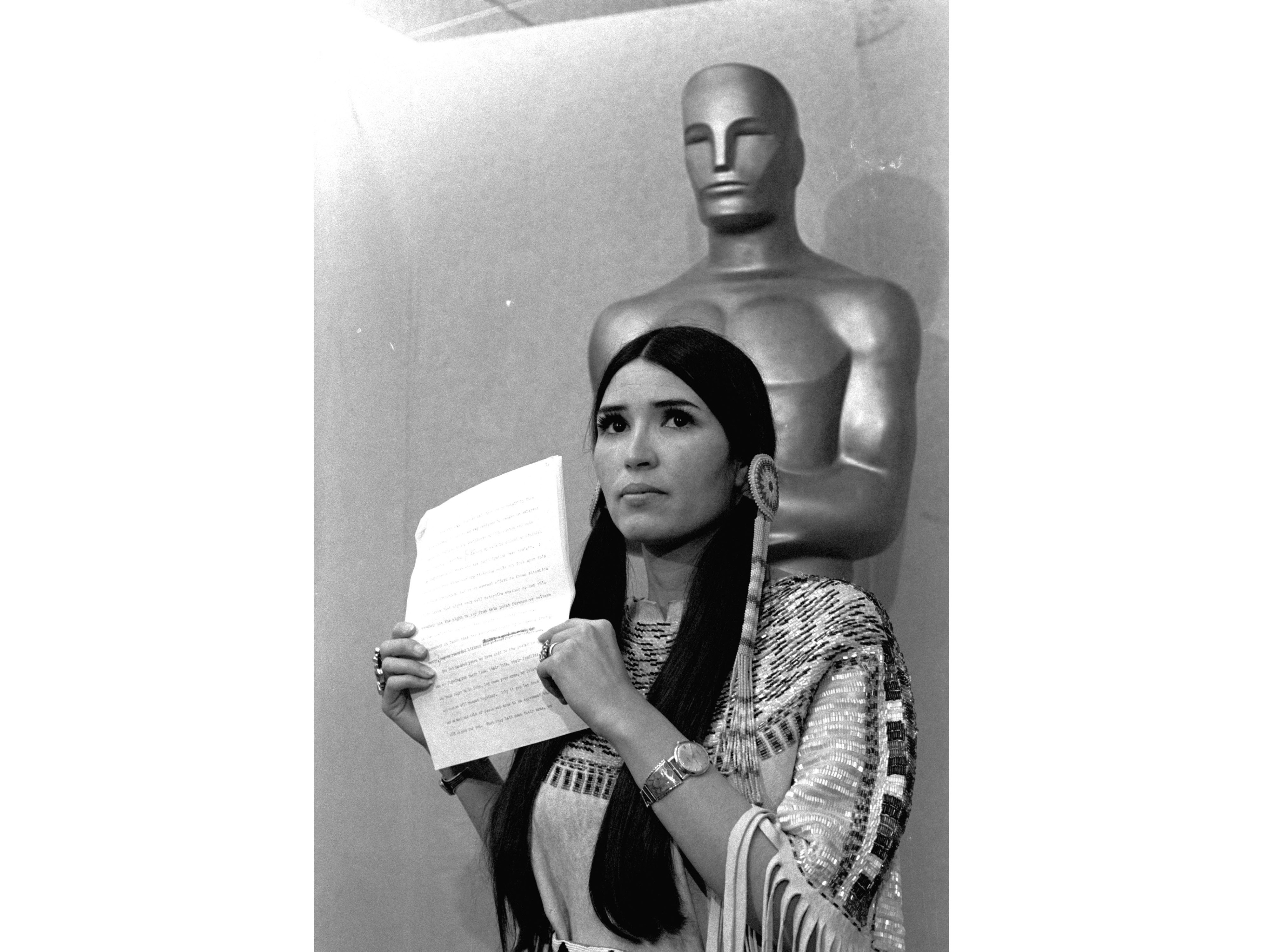 caption: Sacheen Littlefeather appears at the Academy Awards ceremony to announce that Marlon Brando was declining his Oscar as best actor for his role in <em>The Godfather</em>, on March 27, 1973.