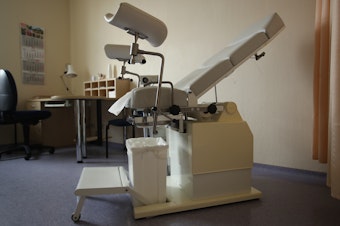 caption: A gynecology chair sits in a doctor's office.