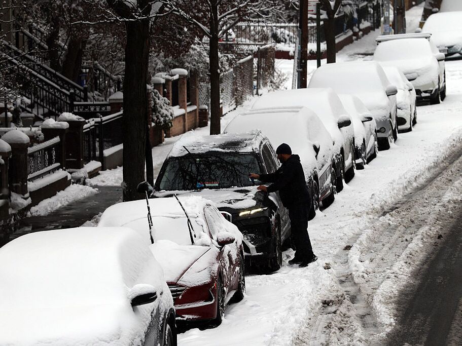 caption: A man cleans off his car of snow in Brooklyn after an overnight storm on Dec. 27, 2025 in New York City.
