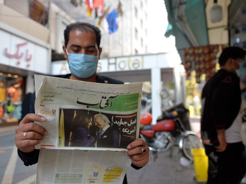 caption: A man reads the news about the U.S. elections on Nov. 9 in Tehran. Many Iranians are hopeful that President Biden will lifts sanctions imposed on Iran by his predecessor.