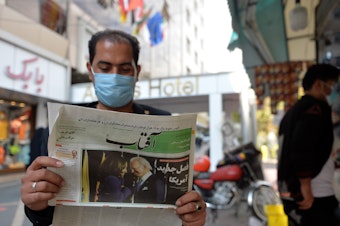 caption: A man reads the news about the U.S. elections on Nov. 9 in Tehran. Many Iranians are hopeful that President Biden will lifts sanctions imposed on Iran by his predecessor.