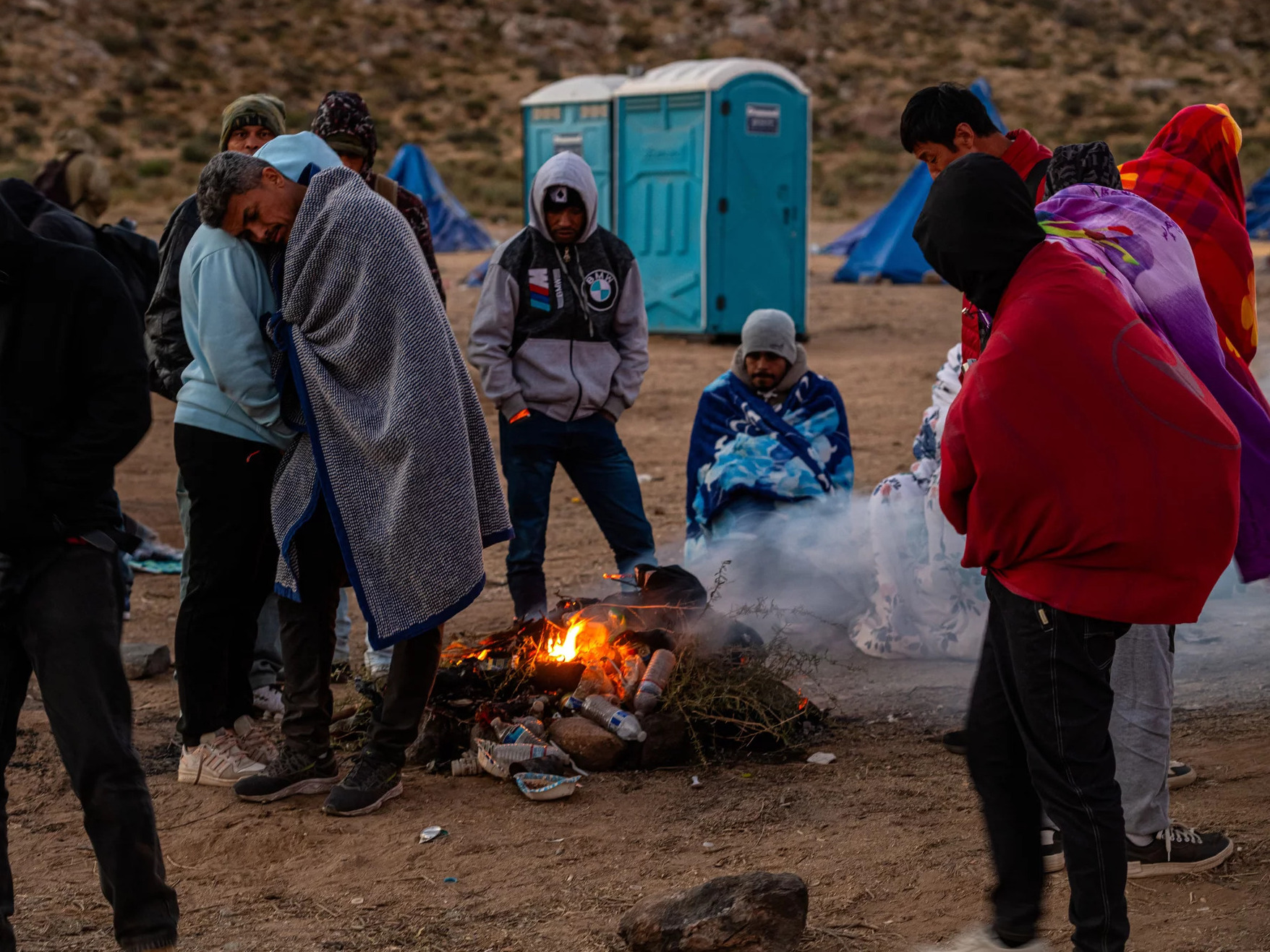 caption: Migrants huddling for warmth at an unofficial detention camp in Jacumba, Calif. A record number of people have arrived at the southern U.S. border in the past year.