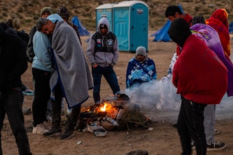 caption: Migrants huddling for warmth at an unofficial detention camp in Jacumba, Calif. A record number of people have arrived at the southern U.S. border in the past year.