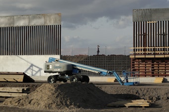 caption: The first panels of levee border wall are seen at a construction site along the U.S.-Mexico border last month in Donna, Texas. The new section, with 18-foot-tall steel bollards atop a concrete wall, will stretch approximately 8 miles.