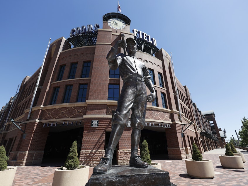 caption: A bronze baseball player stands outside Coors Field in Denver, one of the stadiums idled during the coronavirus outbreak. The league and players association have agreed to league is waiting for the players' union to respond to whether it will agree to play a shortened season beginning in late July.