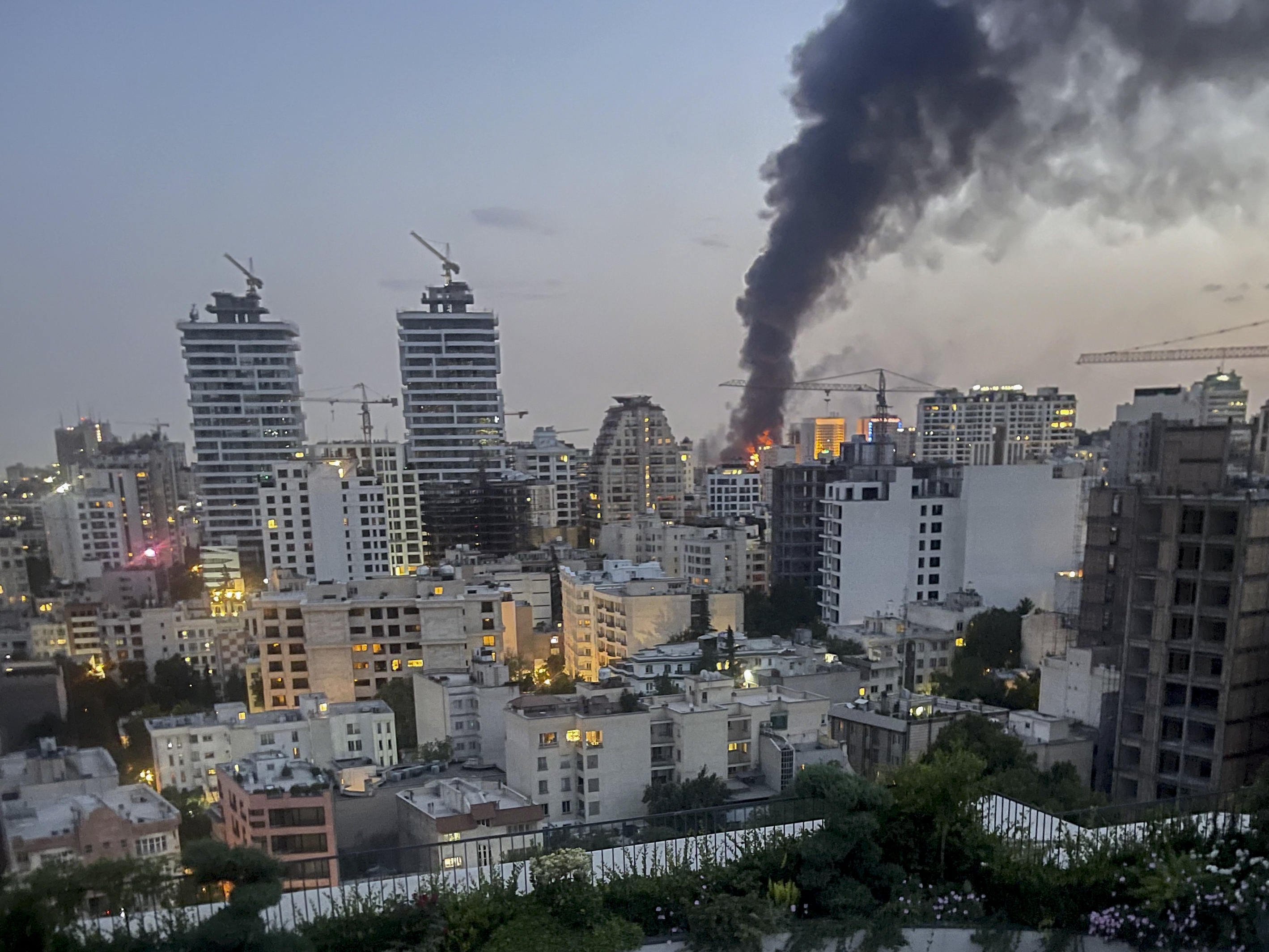 caption: Smoke rises from the rubble of an Iranian state media building in Tehran after an Israeli airstrike on June 16, 2025. The strike, which Israel confirmed targeted "terror-linked propaganda infrastructure," marks a further escalation in regional tensions.