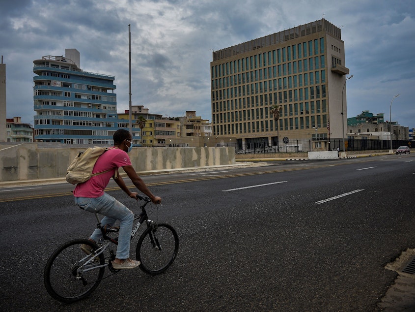 caption: A man rides his bicycle near the U.S. Embassy in Havana on Jan. 12.