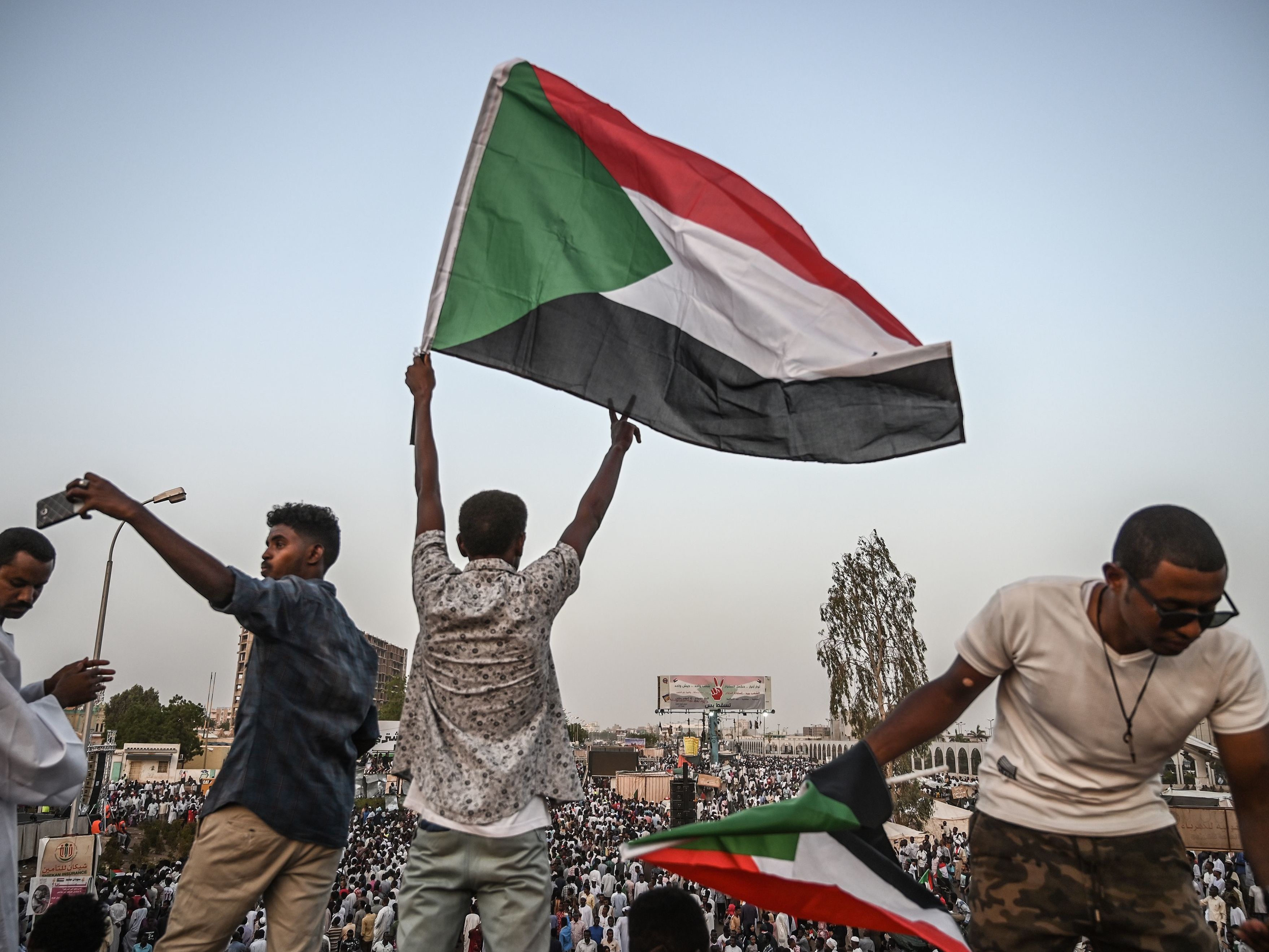 A Sudanese protester waves a national flag on a bridge during a protest outside the army headquarters in the capital Khartoum on April 19, 2019.