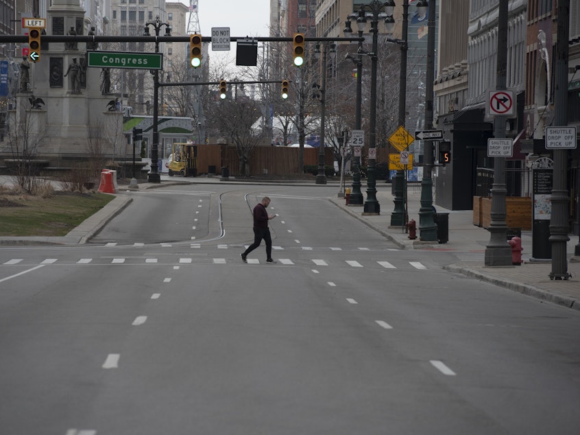 caption: A man crosses an empty street in Detroit, Michigan on March, 24, 2020. - At 12:01 am Tuesday March 24,2020 Governor Gretchen Whitmer ordered a 'Stay at Home and Stay Safe Order' to slow the spread of Coronavirus (COVID-19) across the State of Michigan which now has 1,791 confirmed cases and 24 deaths due to the virus.