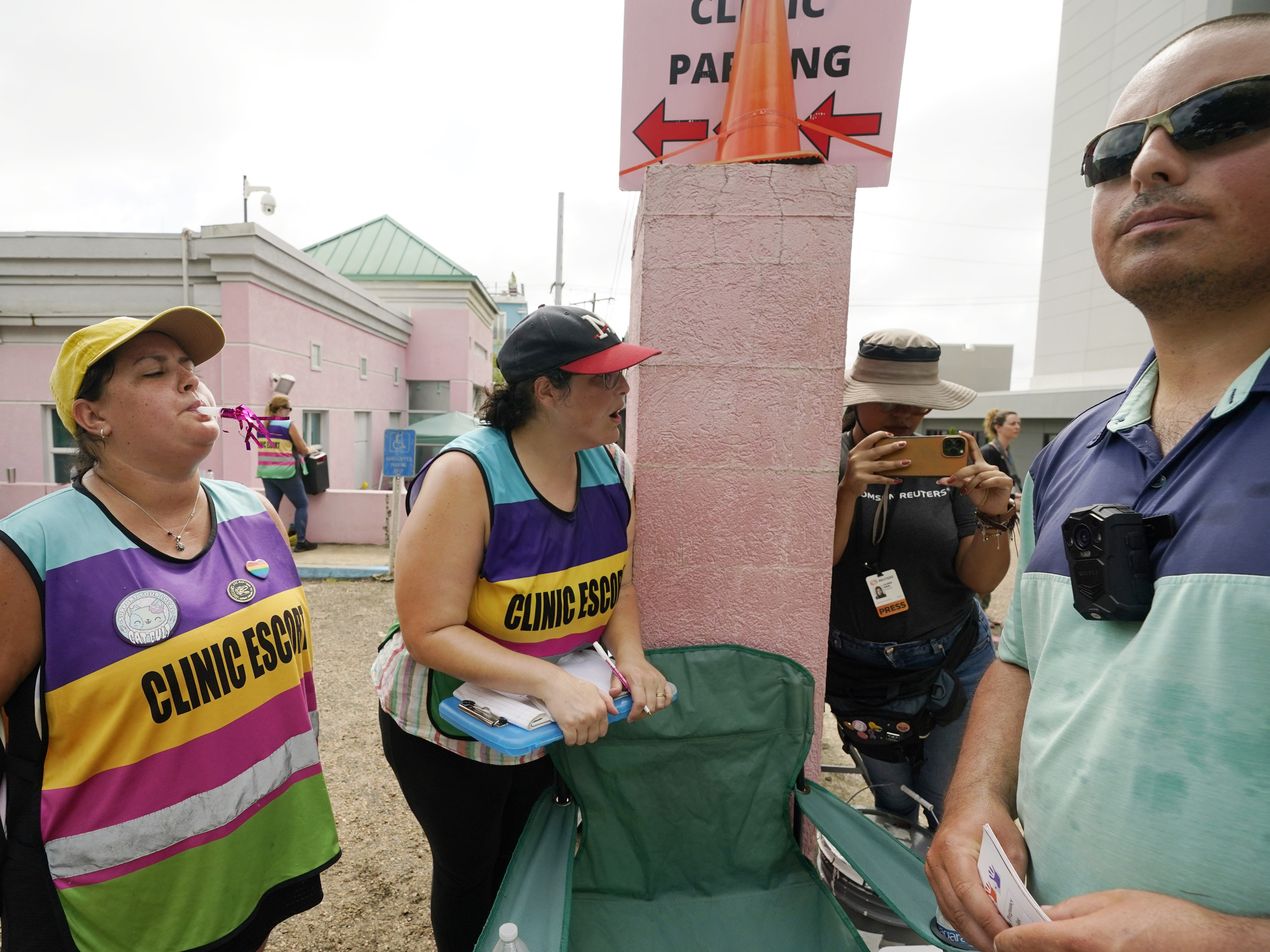 caption: Clinic escorts use party horns and whistles to counter the presence of anti-abortion activist Gabriel Olivier, right, outside the Jackson Women's Health Organization clinic in Jackson, Miss., on July 6, 2022.