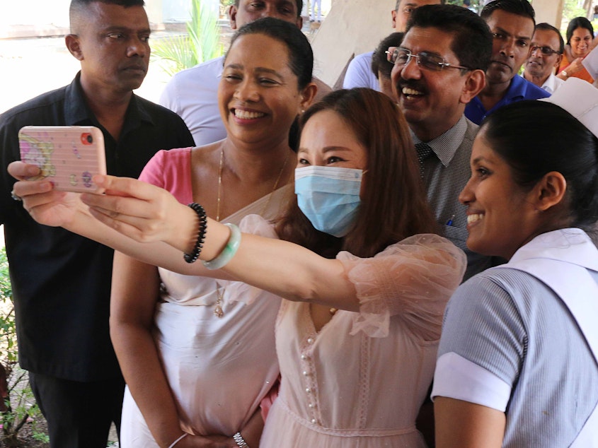 caption: A recovered coronavirus patient takes a selfie before being discharged from a hospital in Sri Lanka. Researchers are trying to determine if having a case of COVID-19 will give you immunity.
