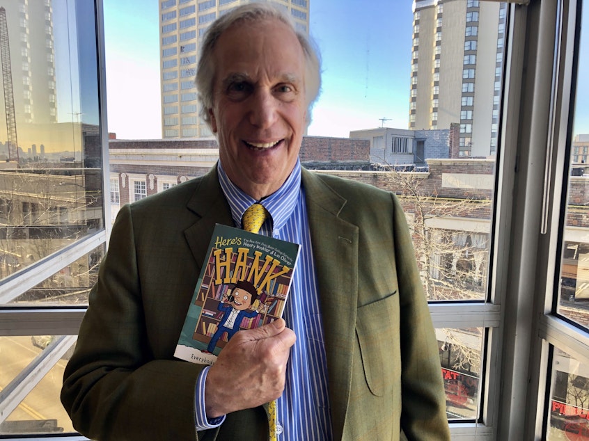 caption: Actor and author Henry Winkler with the final book of 29 (!) in the Hank Zipzer series.