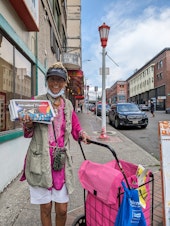 caption: Alganesh Tewelde proudly holds up a copy of International Examiner as she goes out to deliver papers to the neighborhood businesses.