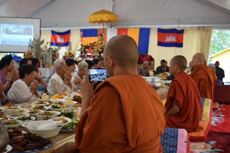 caption: Venerable Prenz Sa-Ngoun snaps photos of a Sunday Buddhist ceremony on his phone. He later posts his photos on Instagram.
