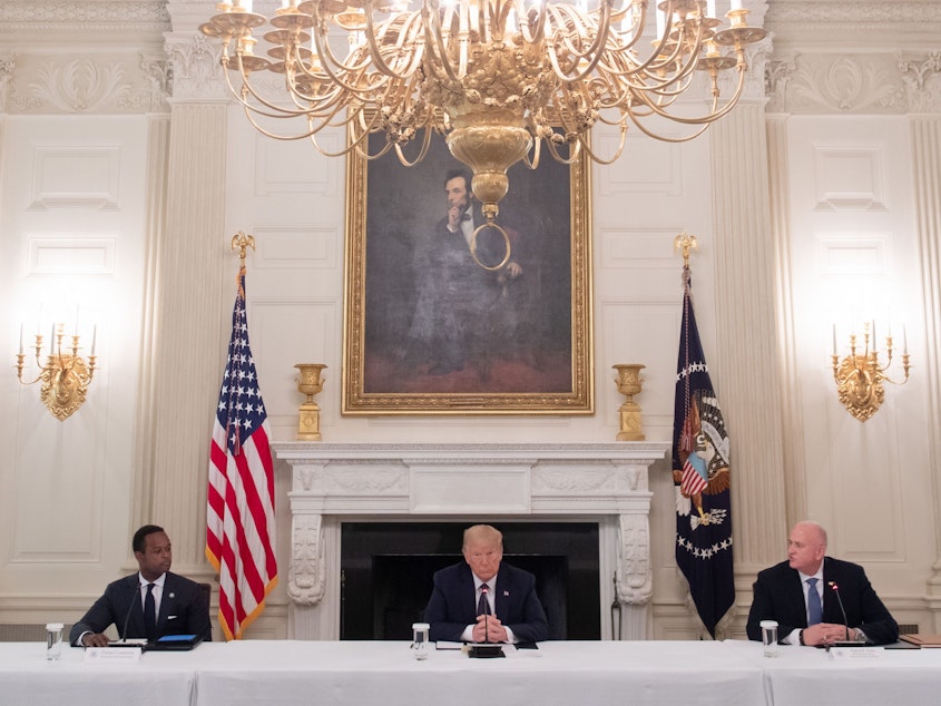 caption: President Trump, center, hosts a roundtable discussion with law enforcement officials on police and community relations in the State Dining Room at the White House Monday.