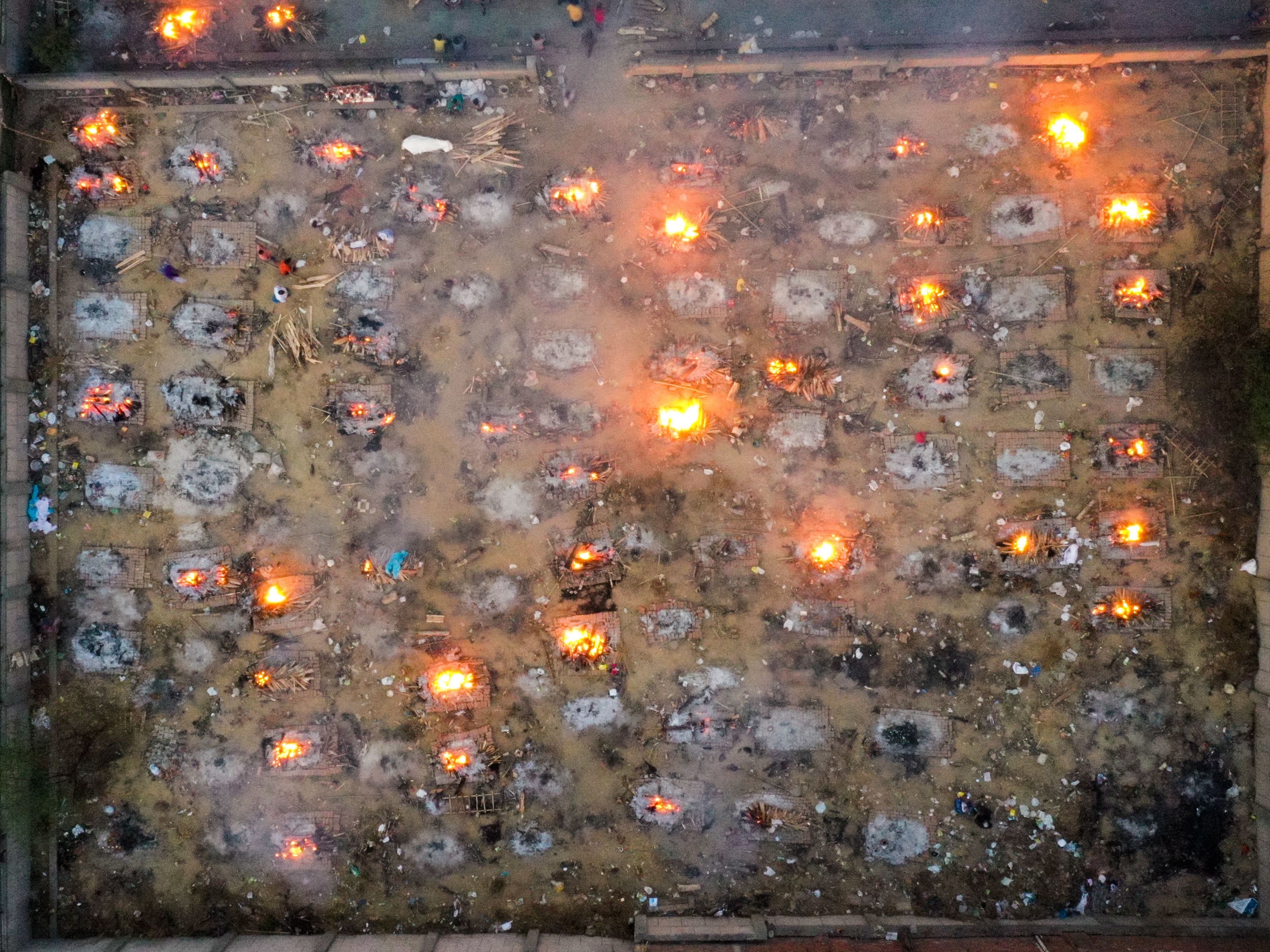 caption: Victims of COVID-19 are cremated in funeral pyres this week in New Delhi. Scientists says the real death toll and number of infections are likely much higher than what the Indian government is reporting.
