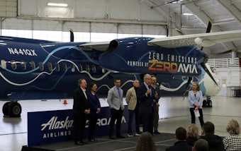 caption: Politicians and corporate leaders gathered in a Paine Field hangar to celebrate the handover of a retired Alaska Airlines Q400 turboprop, which will be converted to hydrogen-electric propulsion over the next year.