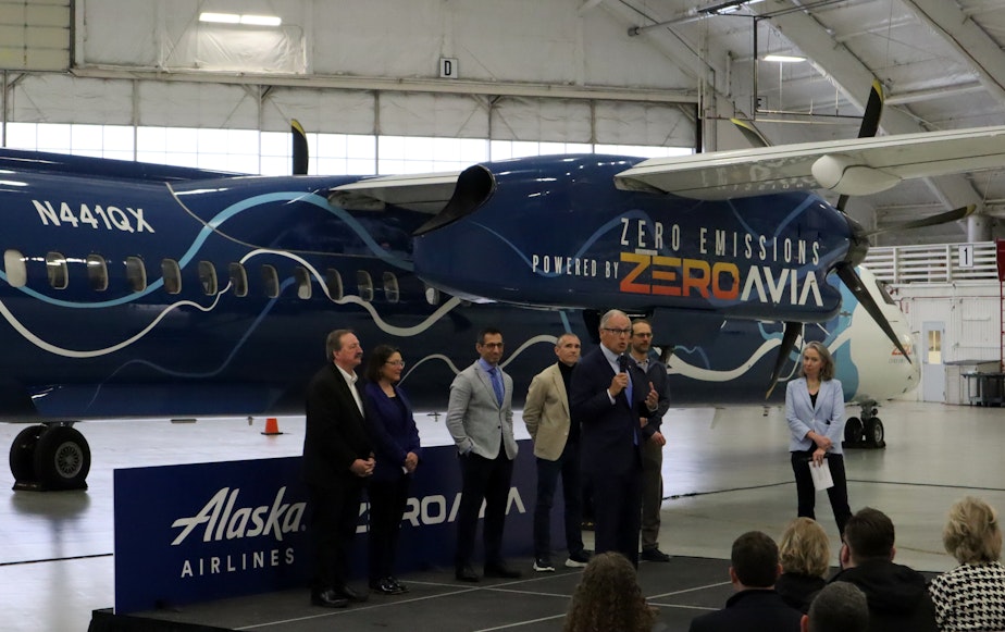 caption: Politicians and corporate leaders gathered in a Paine Field hangar to celebrate the handover of a retired Alaska Airlines Q400 turboprop, which will be converted to hydrogen-electric propulsion over the next year.