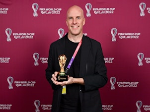 caption: Grant Wahl with a World Cup replica trophy, in recognition of his achievement covering 8 or more FIFA World Cups, during a ceremony at the Main Media Centre on Nov. 29 in Doha, Qatar.