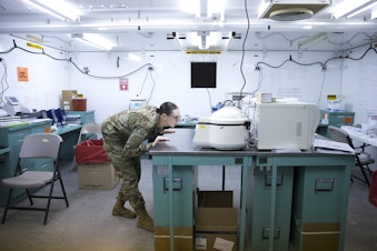 caption: Spc. Ashley Wells, a laboratory technician with the 10th Army Field Hospital, looks into a centrifuge in the laboratory area of the military field hospital inside CenturyLink Field Event Center on Sunday, April 5, 2020, in Seattle. The 250-bed hospital for non COVID-19 patients was deployed by soldiers from the 627th Army Hospital from Fort Carson, Colorado, as well as soldiers from Joint Base Lewis-McChord.