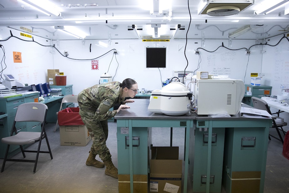 caption: Spc. Ashley Wells, a laboratory technician with the 10th Army Field Hospital, looks into a centrifuge in the laboratory area of the military field hospital inside CenturyLink Field Event Center on Sunday, April 5, 2020, in Seattle. The 250-bed hospital for non COVID-19 patients was deployed by soldiers from the 627th Army Hospital from Fort Carson, Colorado, as well as soldiers from Joint Base Lewis-McChord.