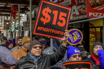 caption: People protest for a $15 minimum wage in New York City in 2017.