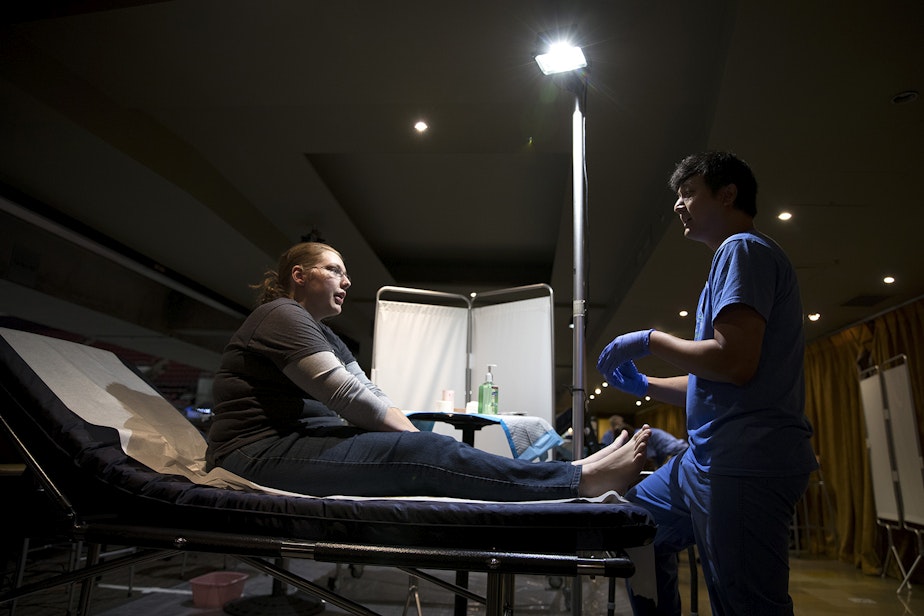 caption: Britta Kauffman speaks to Dr. Paul Sann about a pain in her foot during the Seattle/King County Clinic on Thursday, October 26, 2017, at Key Arena in Seattle.