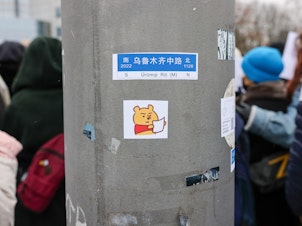 caption: A sticker depicting Winnie the Pooh holding a blank paper was placed on a post as demonstrators protested in front of the Chinese Embassy in solidarity with protesters in China on Saturday in Berlin, Germany.