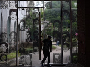 caption: A visitor enters the Officers Casino building at ESMA on March 19, 2016. The windows are filled with images of civilians who were tortured and killed here.