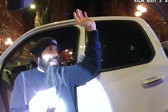 caption: King County Detective Cyrus Bowthorpe raises his hands after being stopped by Seattle police officers, who were unaware that he was working undercover on March 13, 2021.