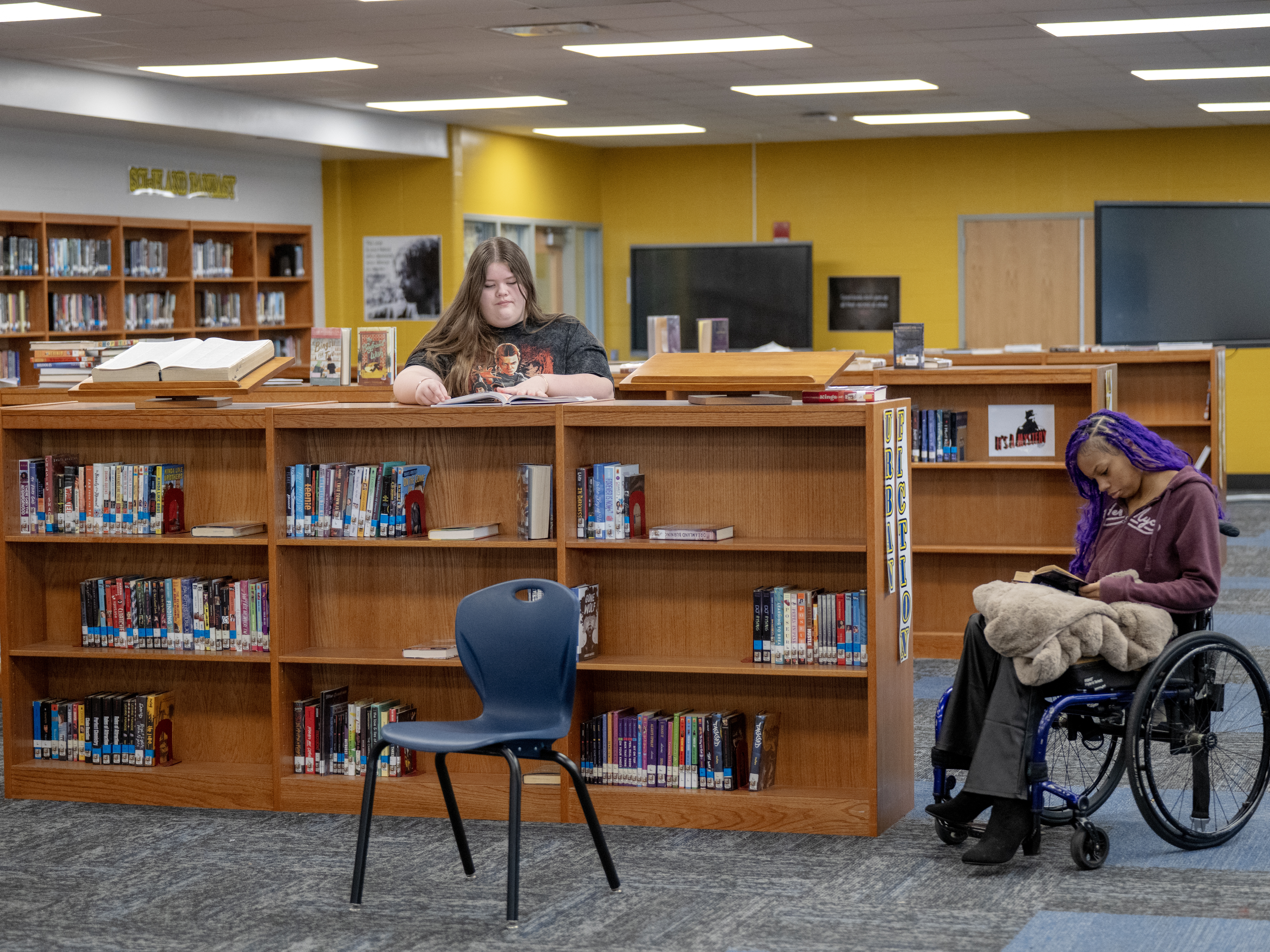 caption: Madelyn Whitt (left) and Quani'e Lanier read in the school library at the Academy @ Shawnee, a magnet middle and high school in Louisville, Kentucky. With cellphones banned at their school, students find other ways to pass time.