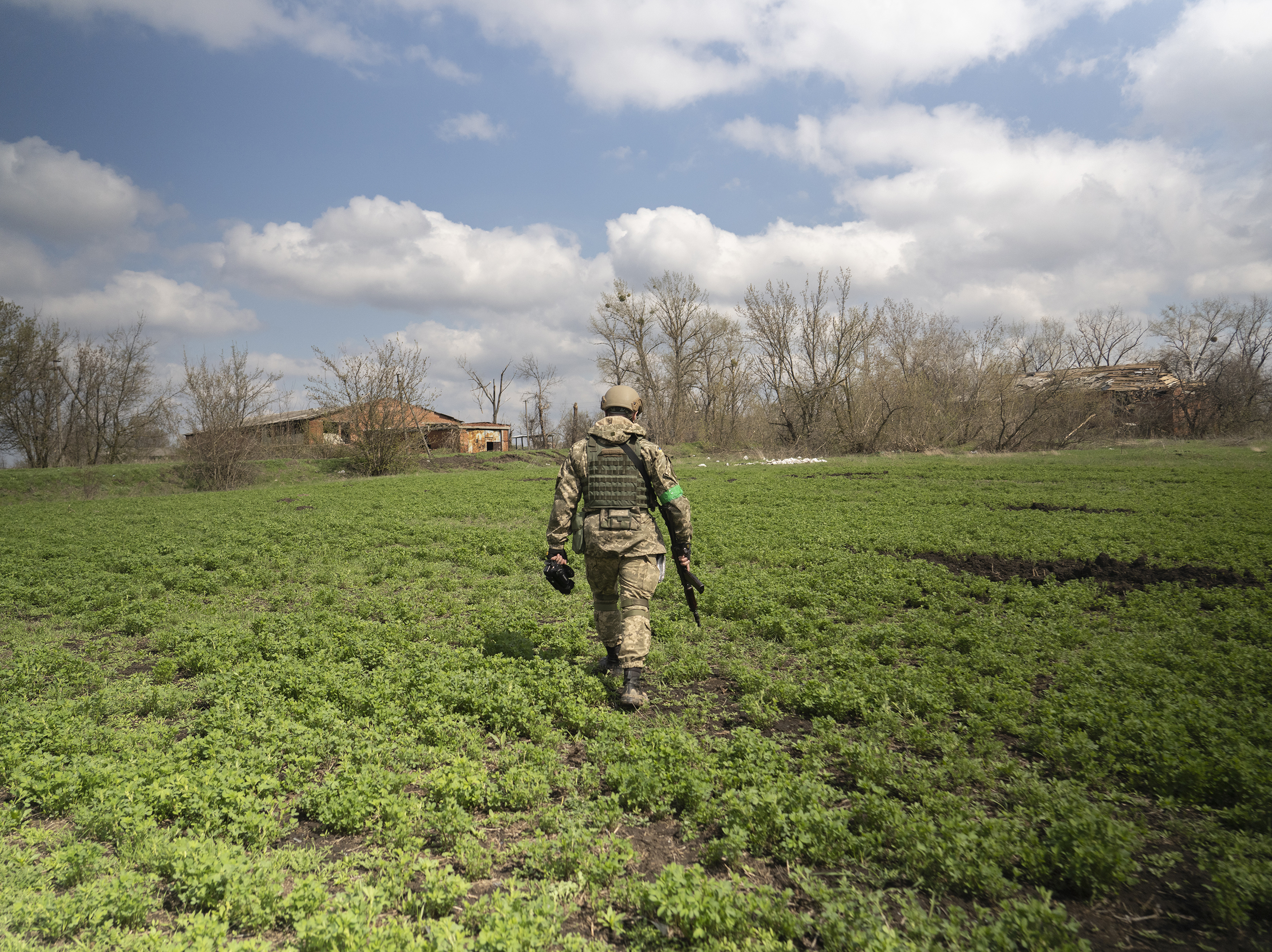 caption: Capt. Daniil, a public affairs officer in the Ukrainian military, walks through a field in Mala Rohan, on the outskirts of Ukraine's northeastern city of Kharkiv. He is recording the aftermath of fighting between occupying Russian soldiers and Ukrainian forces.