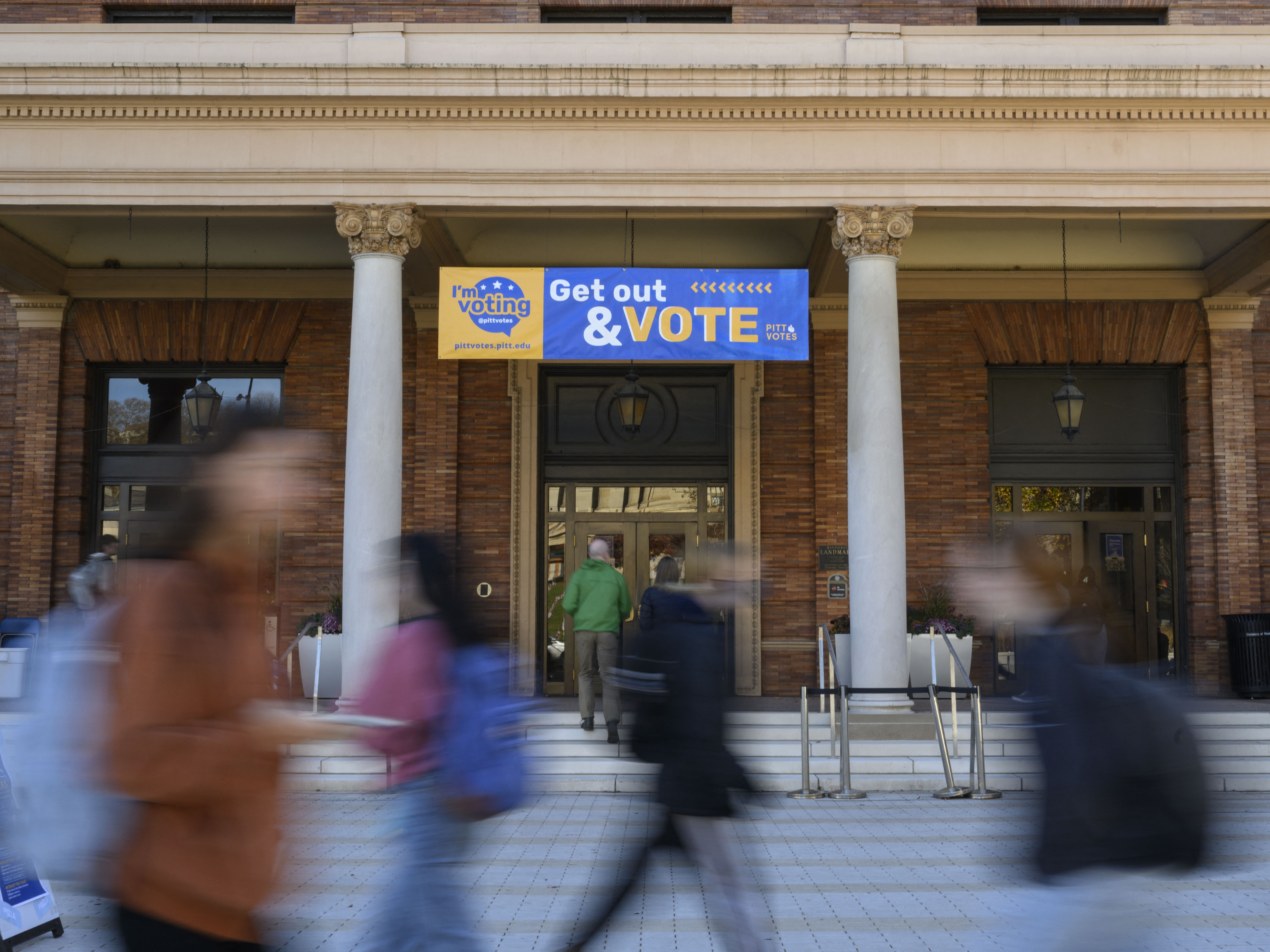 caption: Students walk past a polling site at the University of Pittsburgh during the 2022 midterm election in Pittsburgh, Pa.