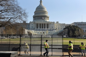 caption: Workers install a fence in front of the U.S. Capitol on Thursday, one day after rioters stormed the building.