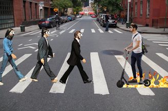 caption: Collage of a three members of The Beatles crossing a street with bugged out eyes as a man on an electric scooter speeds toward them. The scooter is trailing flames in its wake. Photos courtesy of and Canva.