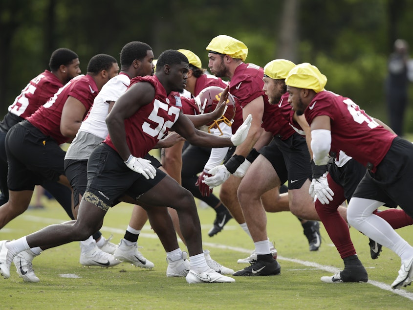 caption: The Washington Football Team during a June practice. The team was one of the last in the league to reach a 50% vaccination threshold among its players.