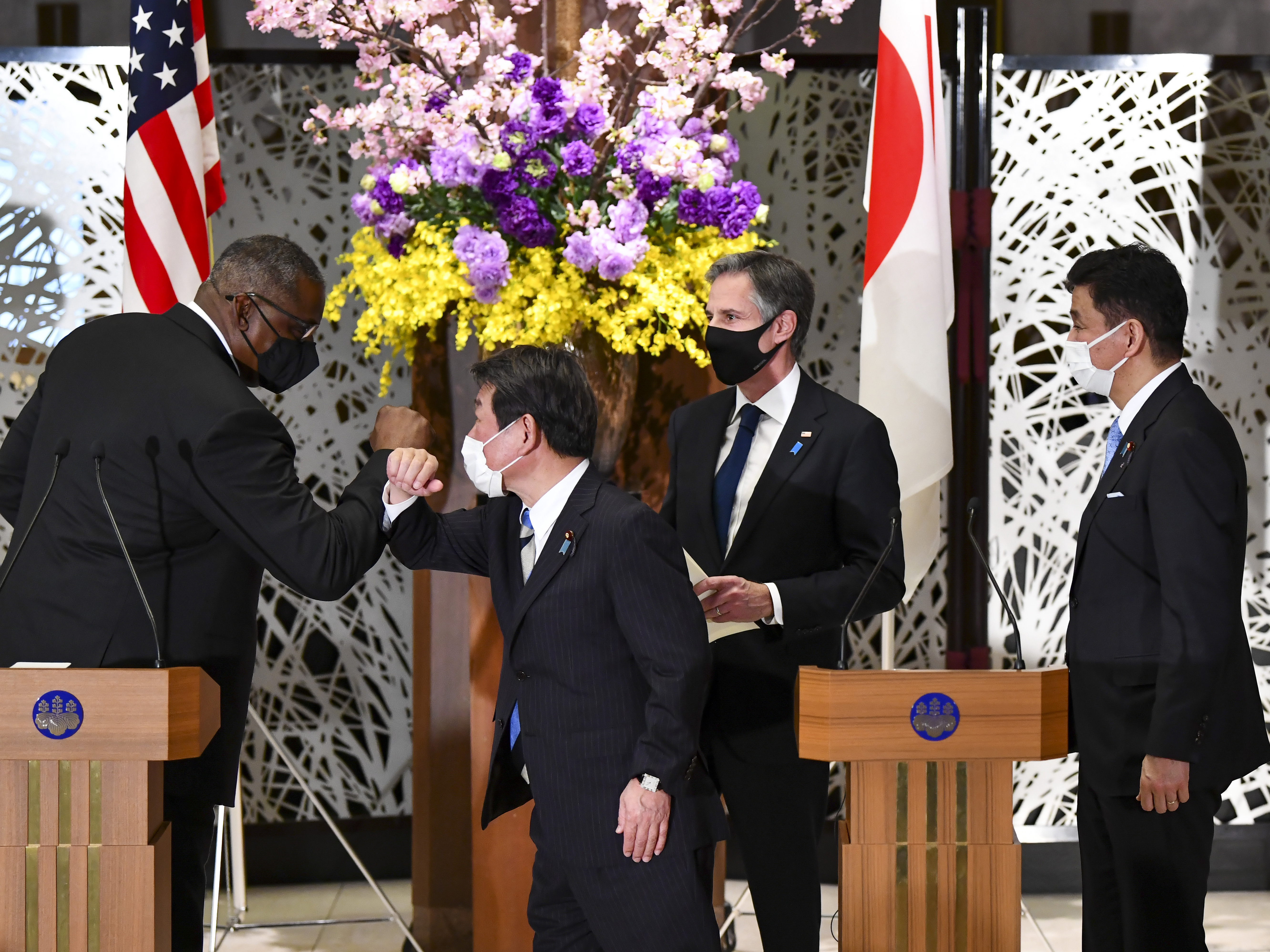 caption: U.S. Defense Secretary Lloyd Austin, left, elbow bumps with Japan's Foreign Minister Toshimitsu Motegi, center, as Secretary of State Antony Blinken and Japanese Defense Minister Nobuo Kishi watch after a joint news conference in Tokyo Tuesday.
